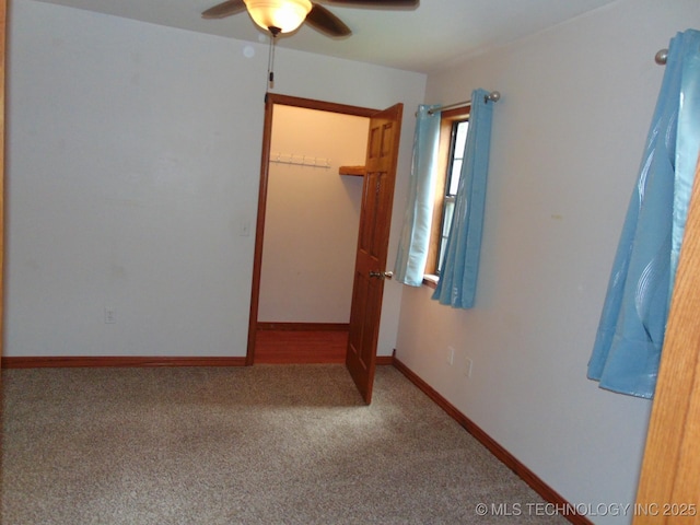 unfurnished bedroom featuring carpet, a walk in closet, a closet, ceiling fan, and baseboards