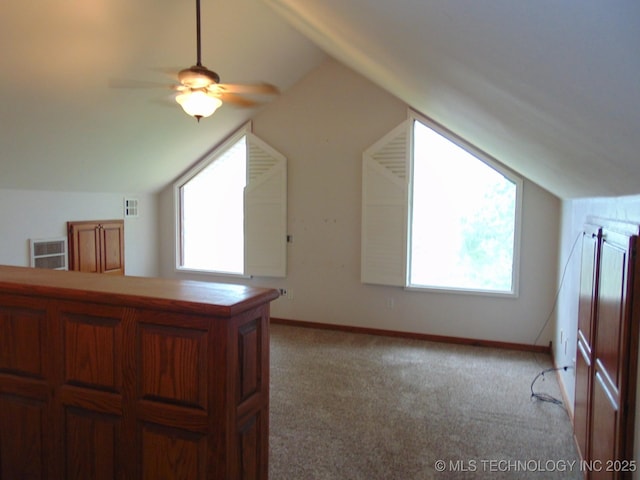 bonus room featuring lofted ceiling, ceiling fan, baseboards, and light colored carpet