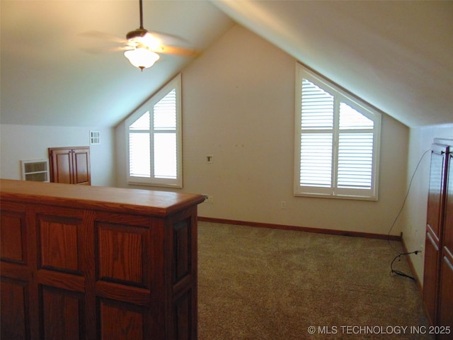 additional living space featuring ceiling fan, healthy amount of natural light, vaulted ceiling, light carpet, and baseboards