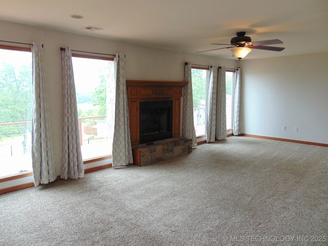 unfurnished living room with a fireplace with raised hearth, carpet, ceiling fan, and baseboards