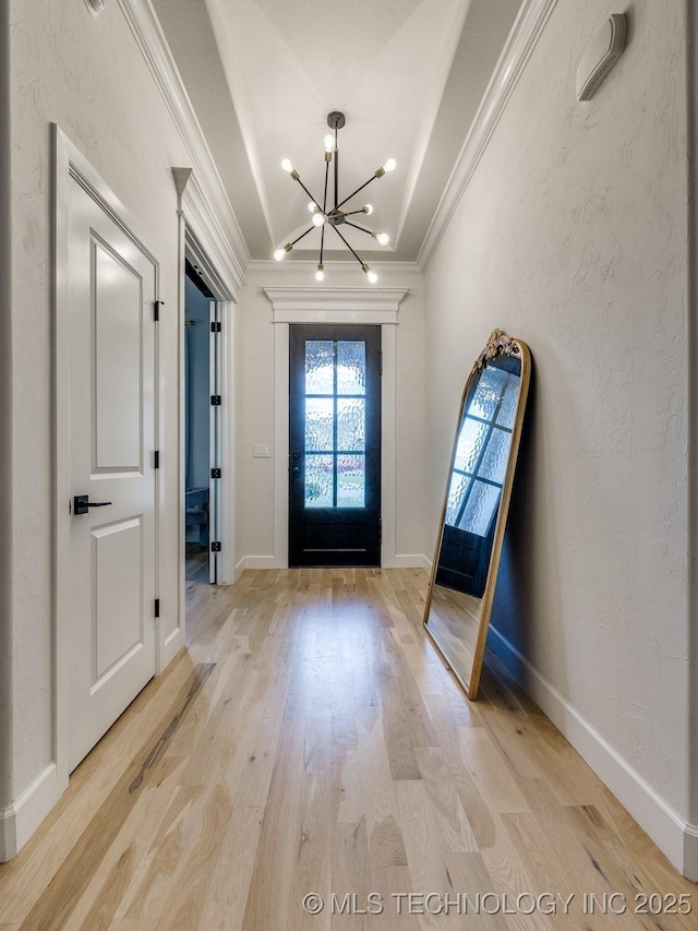 entrance foyer featuring a chandelier, crown molding, light wood finished floors, and baseboards