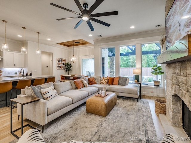 living area featuring ornamental molding, light wood finished floors, a fireplace, ceiling fan, and recessed lighting