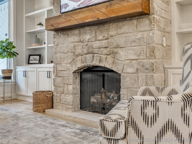 detailed view of wood finished floors, built in features, and a fireplace