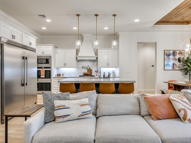 living area featuring ornamental molding, light wood finished floors, and recessed lighting