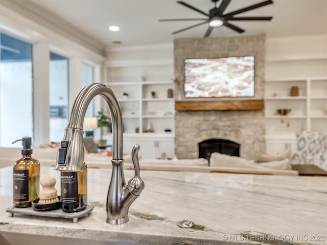 kitchen view of a fireplace, ceiling fan, and built in shelves