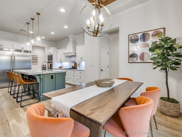 dining space featuring ornamental molding, light wood-style floors, recessed lighting, and a chandelier