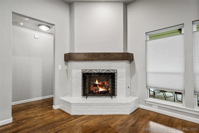 detailed view of a fireplace, baseboards, and wood finished floors