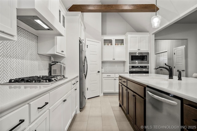 kitchen with appliances with stainless steel finishes, a sink, ventilation hood, light countertops, and vaulted ceiling