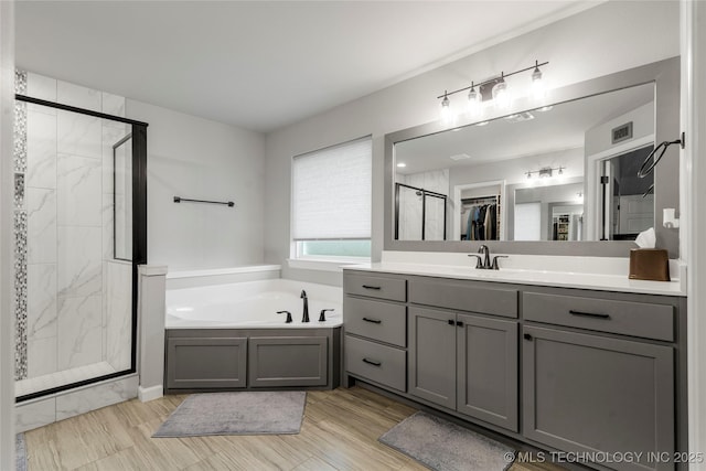 bathroom featuring a stall shower, a bath, and vanity