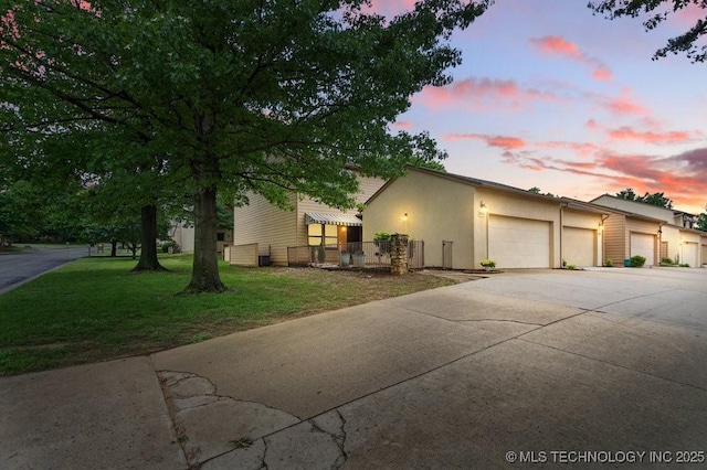 view of front facade featuring a front yard, stucco siding, concrete driveway, and a garage
