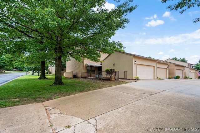 view of front facade with a front yard, stucco siding, and concrete driveway
