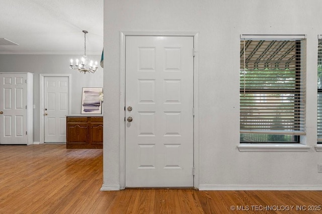 foyer entrance featuring a chandelier, wood finished floors, baseboards, and ornamental molding