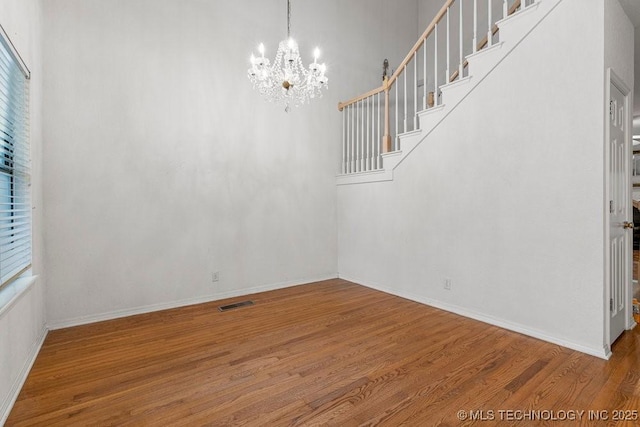 unfurnished dining area featuring a chandelier, wood finished floors, plenty of natural light, and baseboards