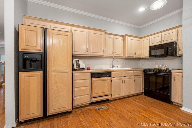 kitchen with black appliances, a sink, light brown cabinetry, light wood-style flooring, and crown molding