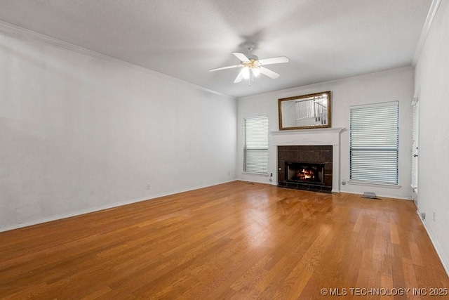 unfurnished living room with light wood-style flooring, a fireplace, a ceiling fan, ornamental molding, and baseboards
