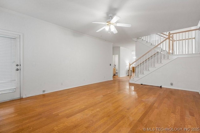unfurnished living room with stairway, ceiling fan, wood finished floors, ornamental molding, and baseboards