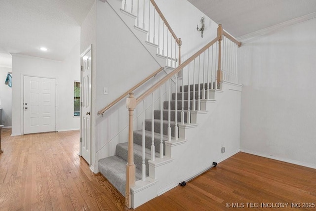 staircase with wood finished floors, baseboards, ornamental molding, and recessed lighting