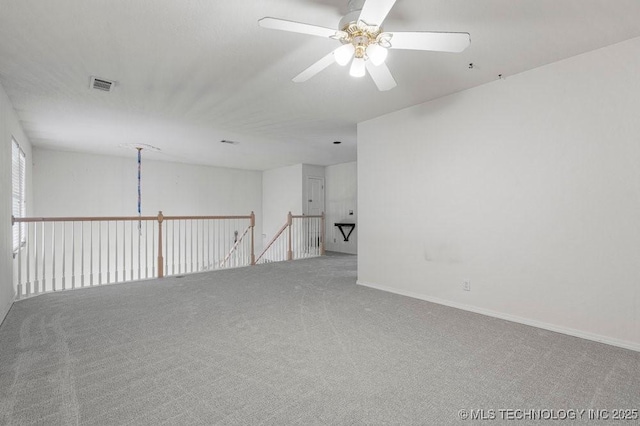 carpeted empty room with a ceiling fan and baseboards
