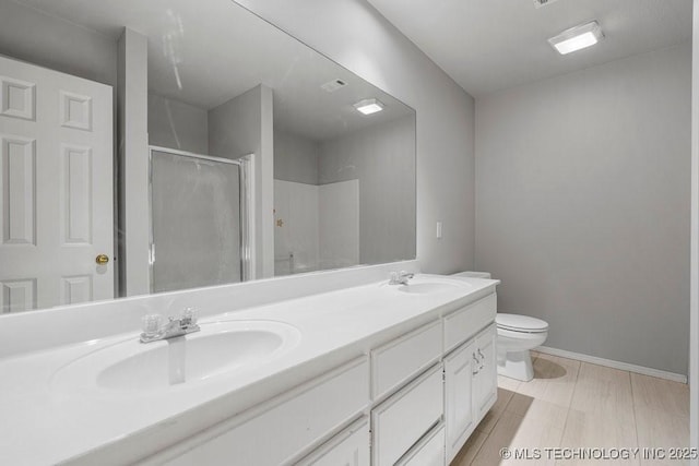 full bath featuring a stall shower, double vanity, toilet, and baseboards
