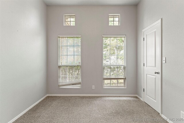 unfurnished room featuring carpet and baseboards
