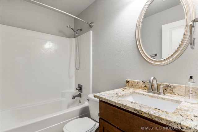 full bath featuring toilet, vanity, bathing tub / shower combination, and a textured wall