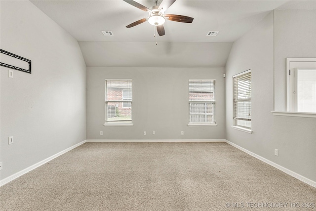 carpeted spare room with vaulted ceiling, ceiling fan, and baseboards