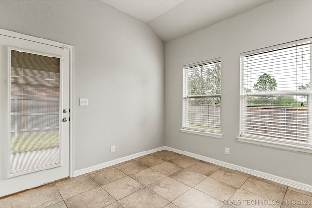 unfurnished room with lofted ceiling, light tile patterned floors, and baseboards