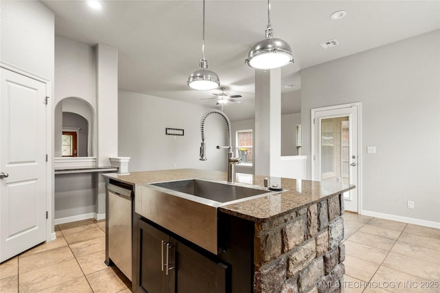 kitchen with light tile patterned flooring, a sink, stainless steel dishwasher, and arched walkways