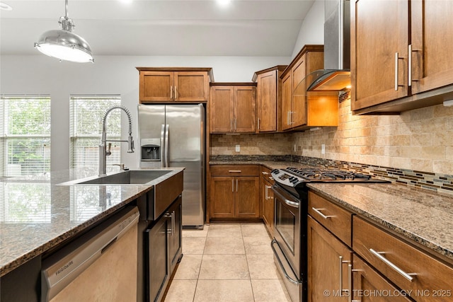 kitchen with appliances with stainless steel finishes, wall chimney range hood, brown cabinetry, tasteful backsplash, and recessed lighting