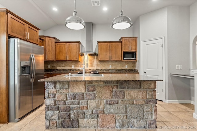 kitchen featuring stainless steel fridge, wall chimney range hood, brown cabinets, built in microwave, and tasteful backsplash