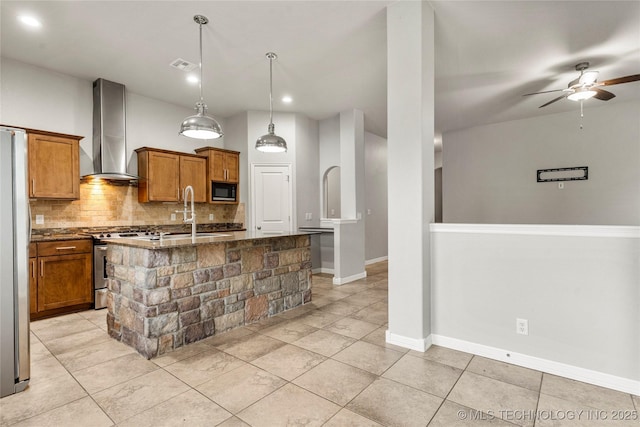 kitchen with wall chimney exhaust hood, appliances with stainless steel finishes, a sink, brown cabinetry, and decorative backsplash
