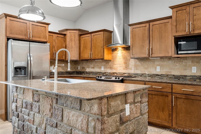 kitchen with a sink, wall chimney range hood, brown cabinetry, dark stone counters, and vaulted ceiling