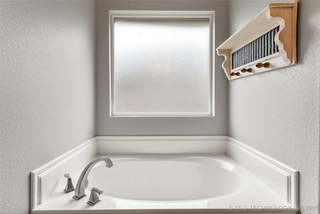 bathroom featuring a garden tub and a textured wall