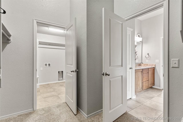 hallway with light tile patterned flooring, a sink, and a textured wall