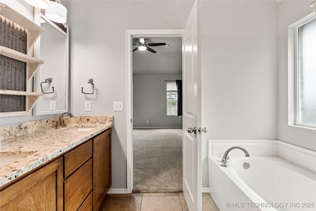 full bath featuring double vanity, tile patterned floors, a garden tub, ceiling fan, and baseboards
