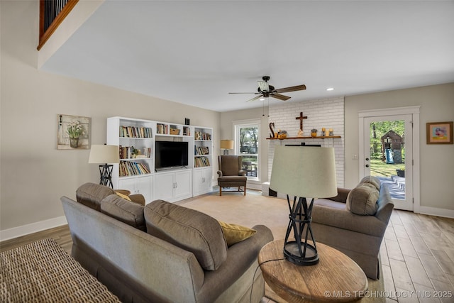 living room featuring light wood-style flooring, baseboards, ceiling fan, and recessed lighting