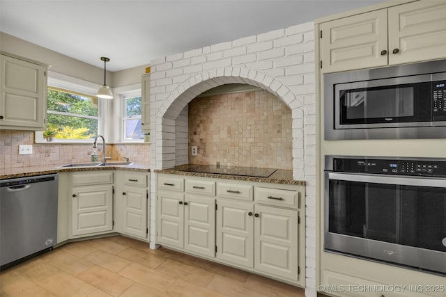 kitchen with stainless steel appliances, a sink, stone countertops, and backsplash