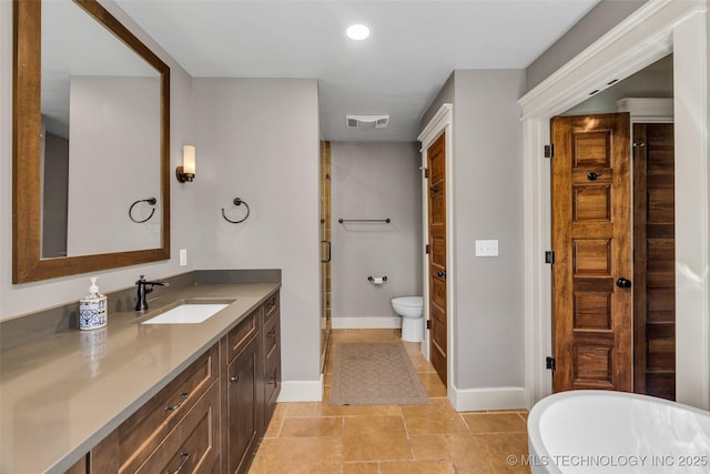 full bathroom featuring baseboards, vanity, a freestanding tub, recessed lighting, and toilet