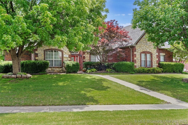 view of front of property with stone siding, a front yard, and a shingled roof