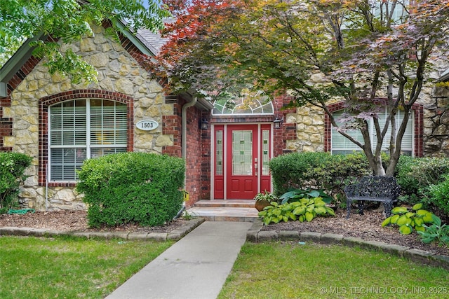 doorway to property with stone siding and brick siding