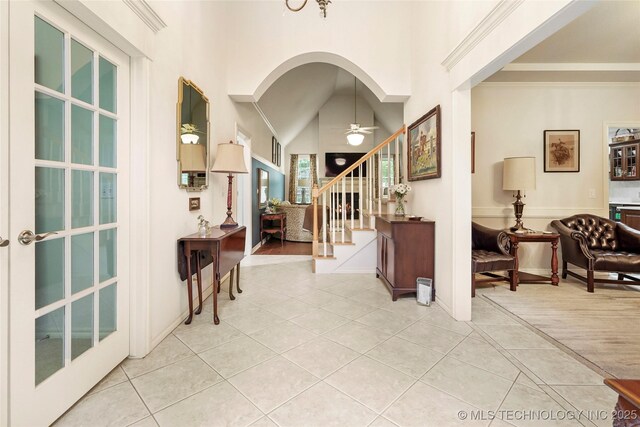 entryway featuring ceiling fan, light tile patterned floors, stairs, a towering ceiling, and baseboards