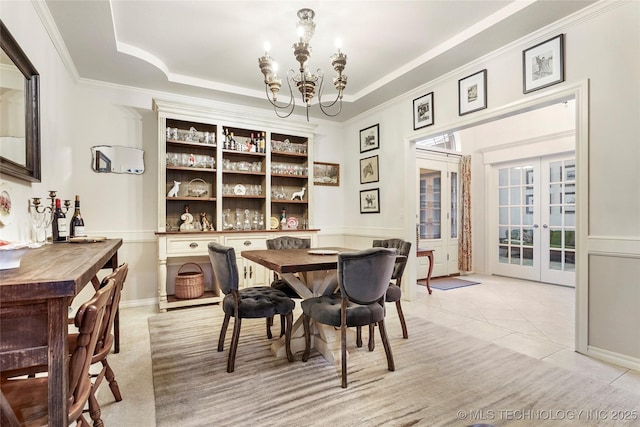 dining area featuring a chandelier, french doors, light tile patterned floors, ornamental molding, and a tray ceiling