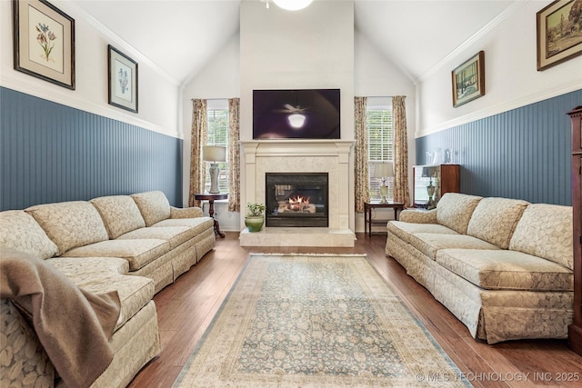 living room featuring a glass covered fireplace, a wainscoted wall, hardwood / wood-style flooring, and high vaulted ceiling
