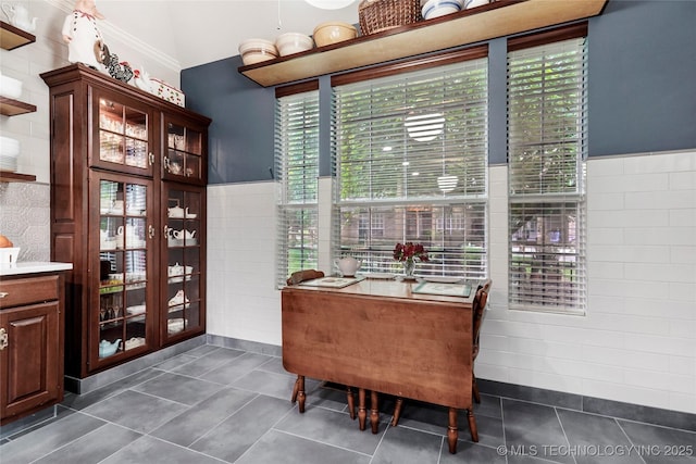 dining area featuring tile walls, dark tile patterned floors, and a wainscoted wall