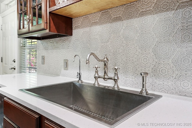 kitchen with light countertops, a sink, and glass insert cabinets