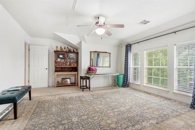 living area with carpet, a ceiling fan, and attic access