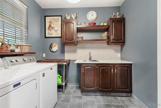 clothes washing area featuring washing machine and dryer, cabinet space, light tile patterned floors, and baseboards