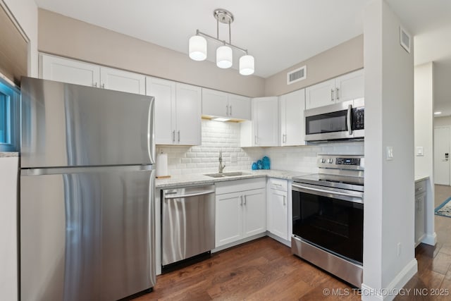 kitchen featuring stainless steel appliances, a sink, dark wood-style flooring, white cabinetry, and backsplash