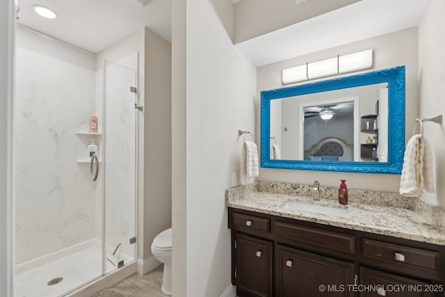 full bath featuring toilet, a marble finish shower, vanity, marble look tiles, and baseboards