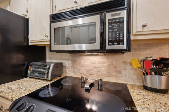 6522 S Memorial Dr Unit 19-H, Tulsa, OK 74133 - kitchen with stainless steel microwave, tasteful backsplash, range, and light stone countertops